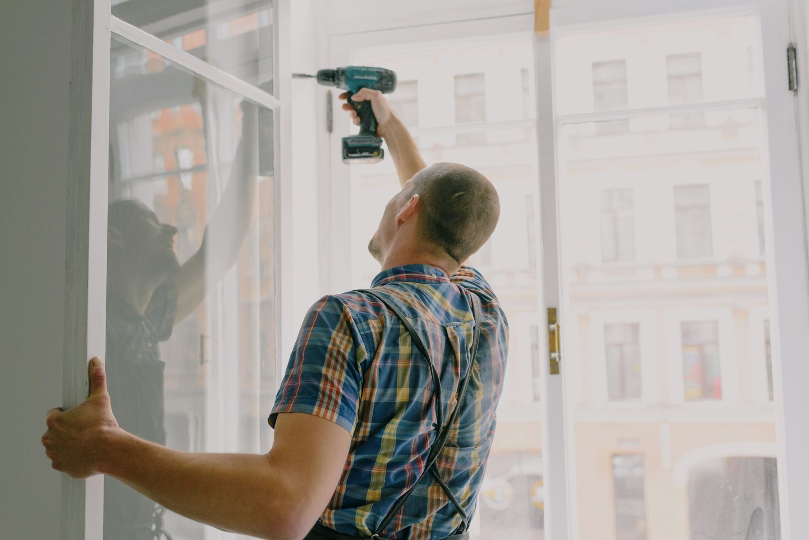 Ouvrier perçant un cadre de fenêtre pendant la pose de menuiseries en rénovation